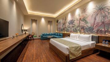A hotel room with a large bed, a sofa, a desk, and a TV.