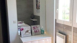 Une chambre avec une commode blanche, un miroir et une fenêtre.