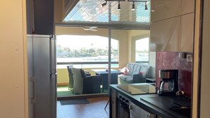 Une cuisine moderne dotée d’un four encastré, d’une machine à café et offrant une vue sur un balcon aménagé avec du mobilier d’extérieur.