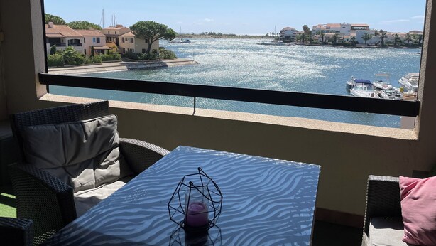 Un balcon offrant une vue sur une marina et sur les bâtiments situés de l’autre côté de l’eau.