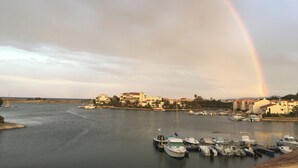 Un port de plaisance avec des bateaux amarrés, un arc-en-ciel dans le ciel et des bâtiments en arrière-plan.