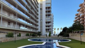 Un hotel moderno con piscina central y varios balcones.
