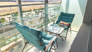A balcony with two chairs and a table, overlooking a cityscape. - Bloomfields Lavish STU in Oasis Masdar (Abu Dhabi)