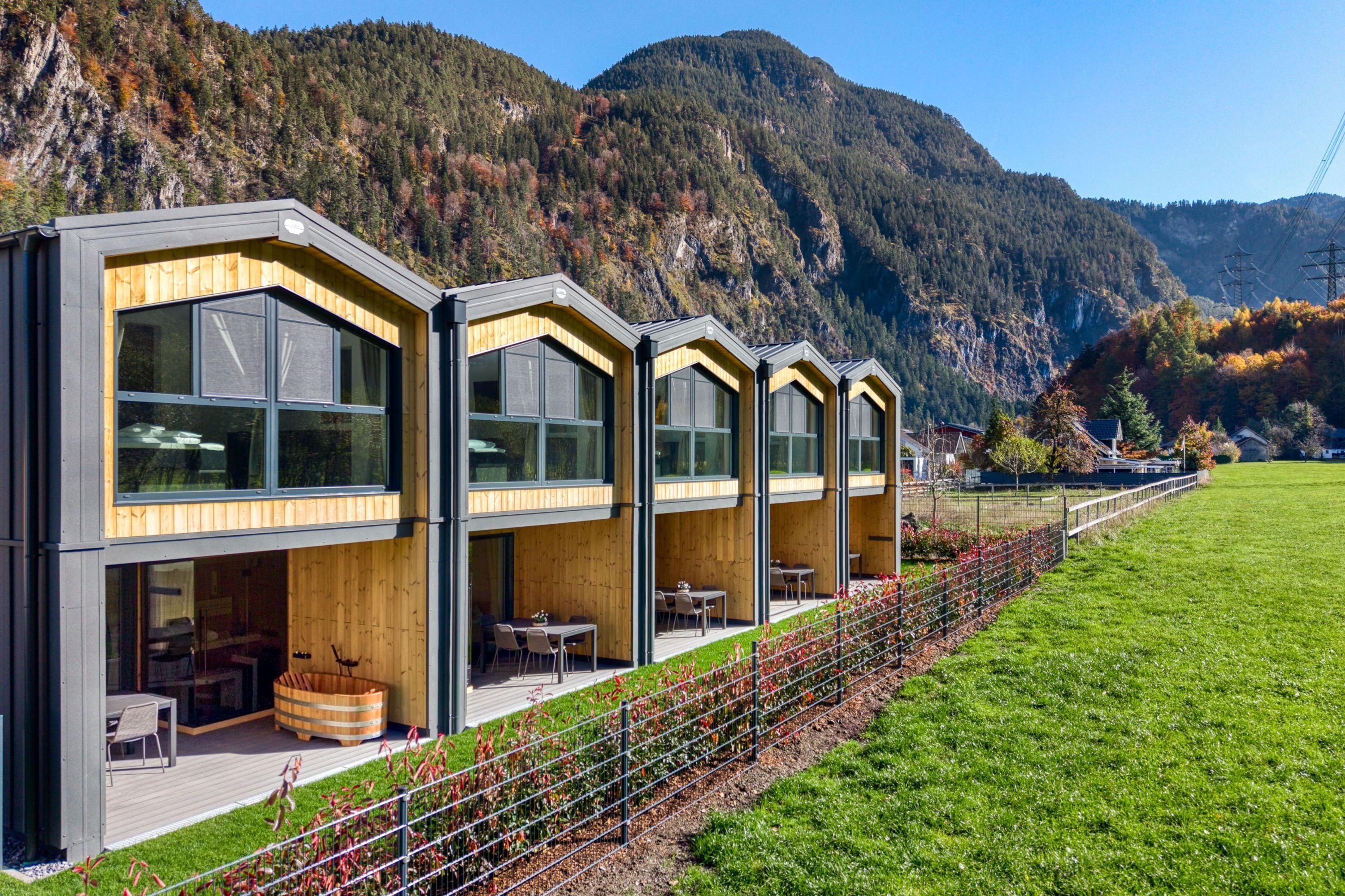 A modern building with large windows, wooden accents, and a view of a mountainous landscape.