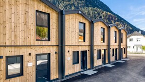 A row of wooden cabins with black-framed windows and doors, set against a mountainous backdrop. - Bsundrix Wellness Tiny Vaya (Lorüns)