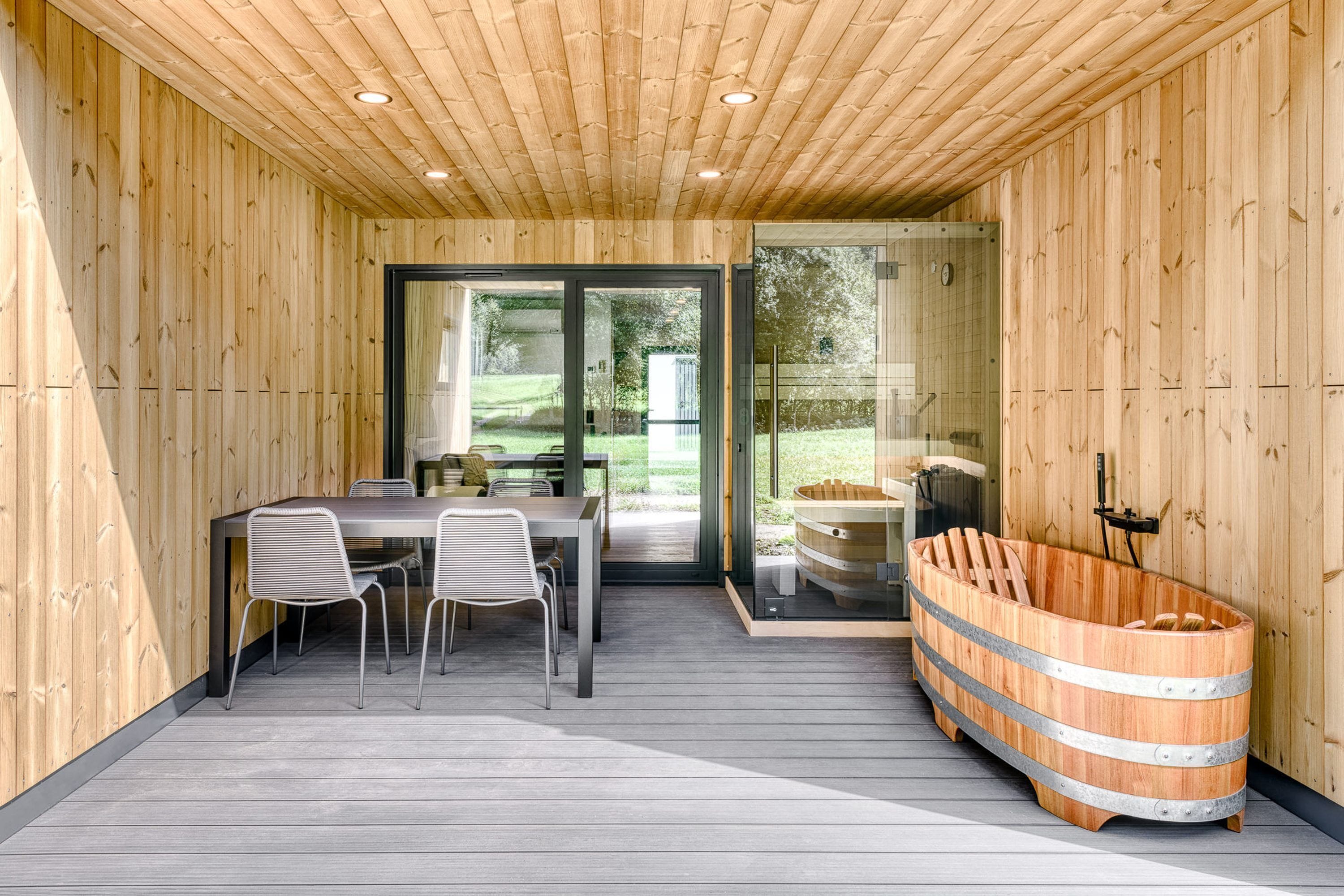 A wooden interior with a dining area, a sauna, and a glass door leading outside.