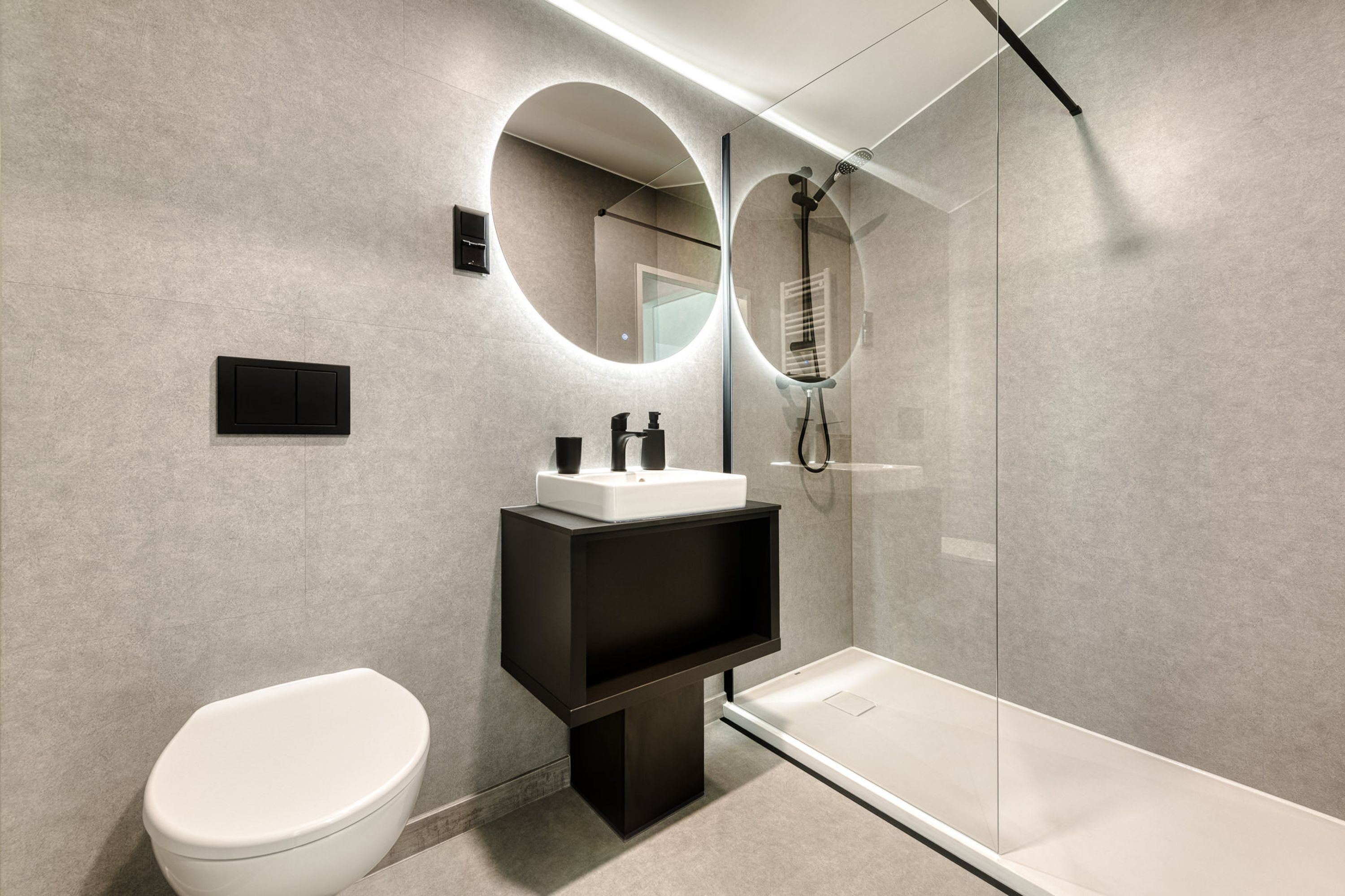 Un bagno moderno con il water, un lavandino, uno specchio e una cabina doccia in vetro.