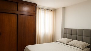 Een slaapkamer met een bed, een houten garderobe en een raam met gordijnen.