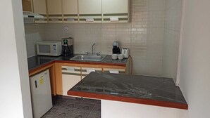 Een kleine keuken met een magnetron, koffiezetapparaat, broodrooster en een spoelbak.