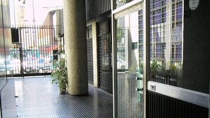 Een moderne gevel met een metalen hek, een betonnen pilaar en een plant in een pot.