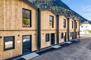 A row of wooden cabins with black-framed windows and doors, set against a mountainous backdrop. - Bsundrix Living Tiny Skadi (Lorüns)