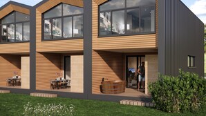 A modern multi-story house with large windows, a wooden exterior, and a well-maintained garden.