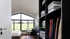 A modern bedroom with a large window, a bed, a desk, and a wardrobe.