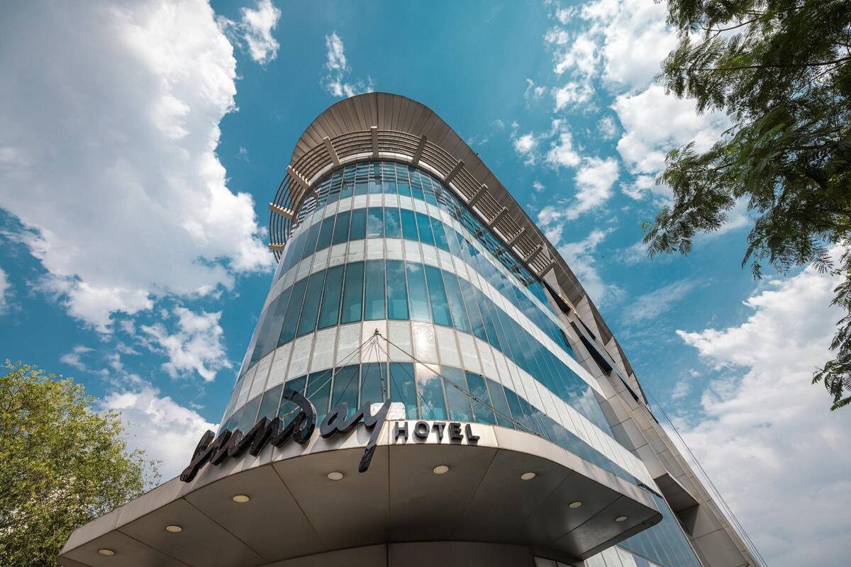 Ein modernes Hotel mit einer geschwungenen Glasfassade und blauem Himmel im Hintergrund.