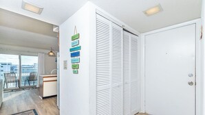 A modern interior with a kitchen area, a sliding door closet, and a view through a glass door to an outdoor balcony.