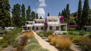 A two-story building with a garden pathway leading to the entrance. - Votsalo Sea Side (Andros)