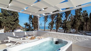 A spa area with a hot tub, lounge chairs, and a view of the sea. - Votsalo Sea Side (Andros)