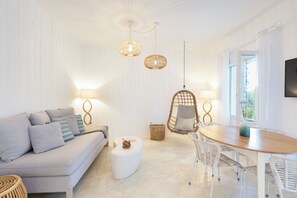 A modern living room with a sofa, a dining table, and hanging lights. - Votsalo Sea Side (Andros)