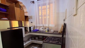 A compact kitchen with a stove, sink, and wooden cabinets. - NYALI 1BR/Hot Shower/AC/Parking behind Quickmart (Mombasa)