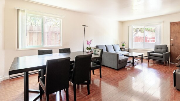 Een ruime woonkamer met een eettafel, stoelen, een bank en een salontafel.