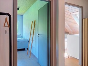 A room with a bed, a ladder, and a door leading to another room.