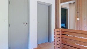 A hallway with two closed doors, wooden flooring, and a bench.