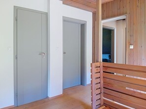 A hallway with two closed doors, wooden flooring, and a bench.