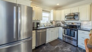 Una cocina moderna con electrodomésticos de acero inoxidable, armarios blancos, un microondas y un horno doble.