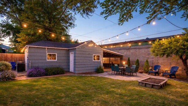 Un patio trasero con porche techado, mobiliario exterior e iluminación con luces colgantes.