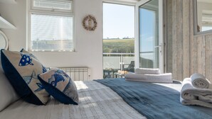 A bedroom with a bed, a radiator, a window with blinds, a door leading to a balcony, and a view of the outdoors. - Wonderful private villa for 6 guests with WIFI, TV, terrace and pets allowed (Mevagissey)