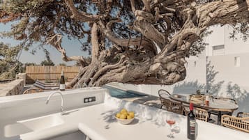 A kitchen area with a sink, a bowl of lemons, a wine bottle, and a glass of red wine.