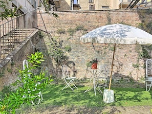 A brick wall with a metal staircase, a white umbrella, and outdoor furniture.