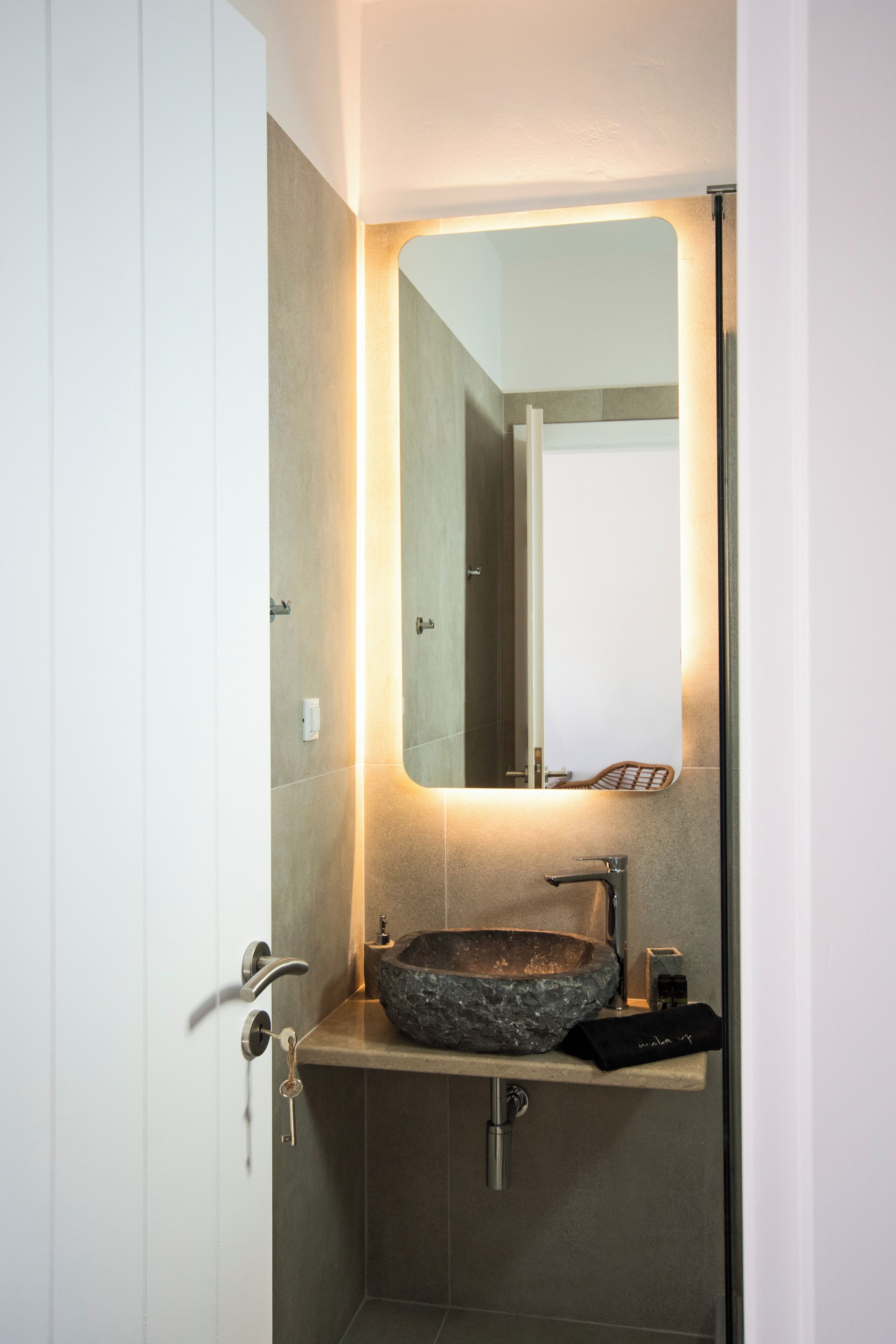 A modern bathroom with a stone sink, a mirror, and a towel rack.