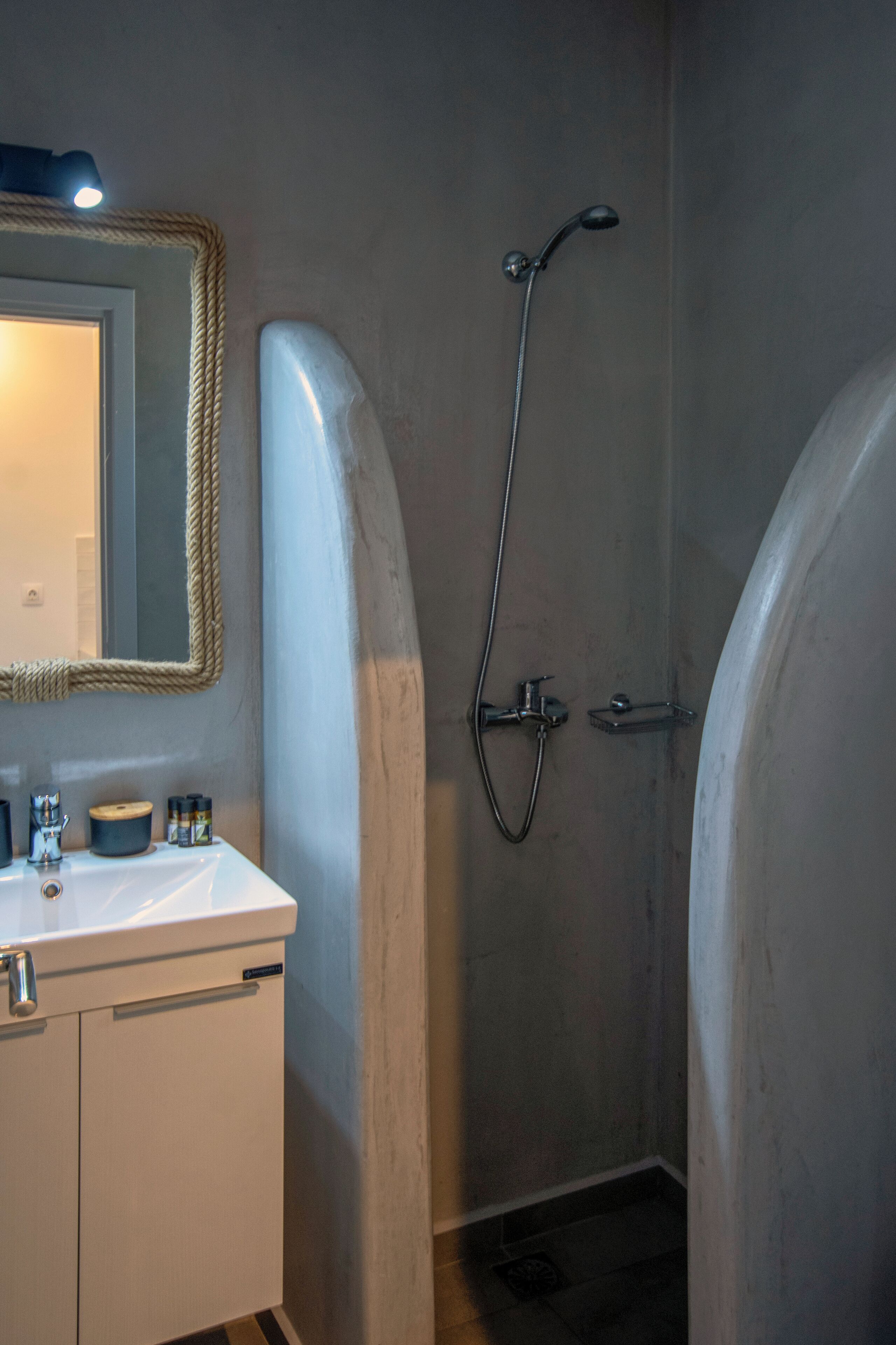 Een badkamer met een witte wastafel, spiegel en douche.