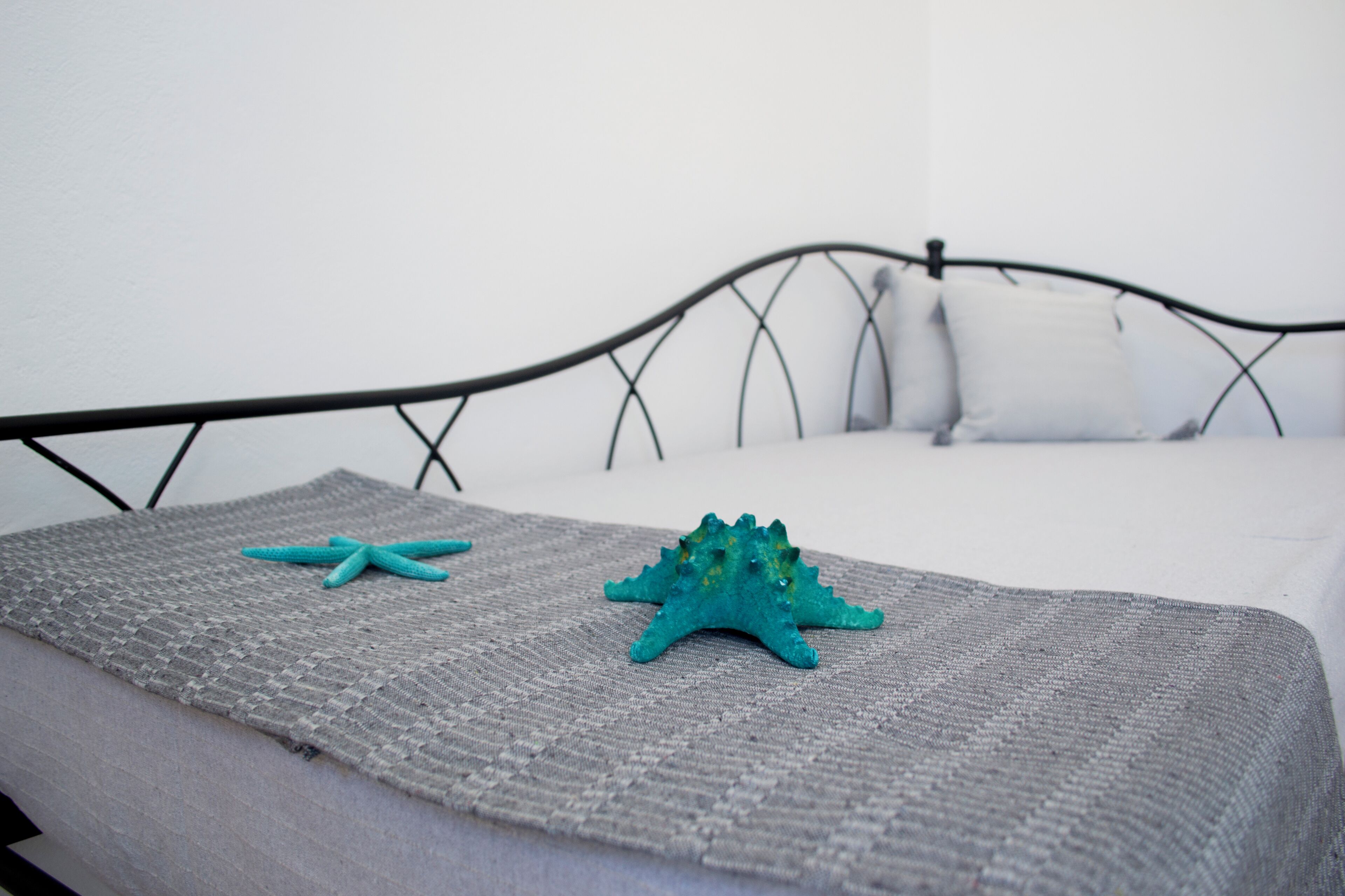 A bed with a grey blanket and two decorative items on it.