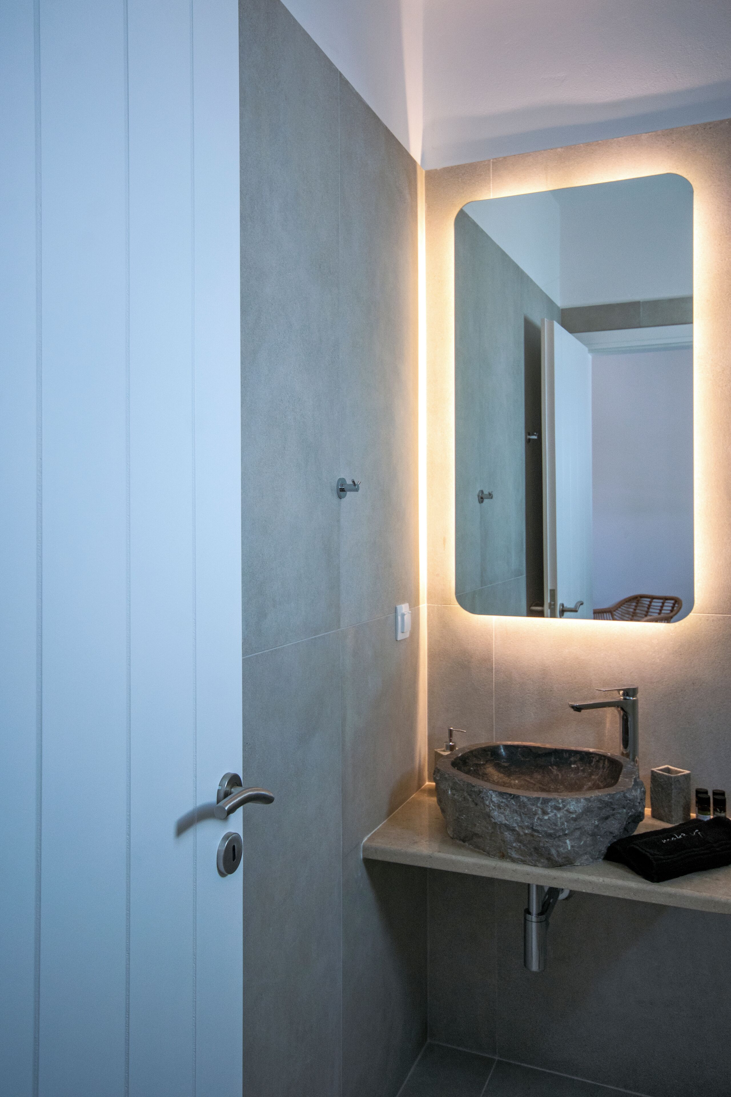 A bathroom with a stone sink, a mirror, and a door.