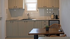 Una cocina compacta con armarios de colores claros, una ventana pequeña y un comedor con mesa y sillas.