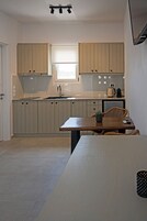 Una cocina compacta con armarios de colores claros, una ventana pequeña y un comedor con mesa y sillas.
