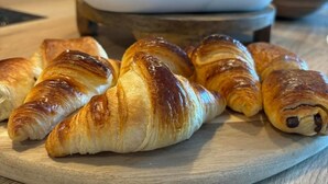 Una mesa de madera con cruasanes y una cafetera en una cocina.