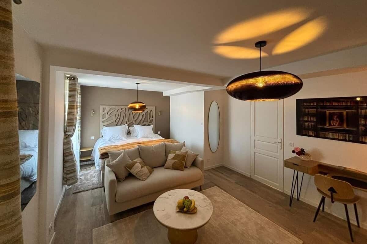 A modern bedroom with a bed, a sofa, a desk, and a dining area.