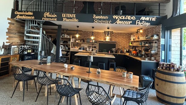 Un restaurante con interior de madera, una mesa larga con sillas y un letrero con texto en francés.