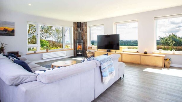 A modern living room with a large white sofa, a flat-screen TV, and a fireplace.