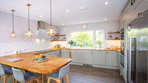 A modern kitchen with a wooden island, stainless steel appliances, and pendant lighting.