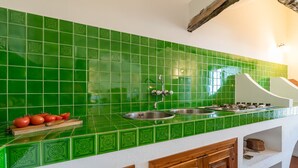A kitchen with green tiles, a sink, a stove, and wooden cabinets. - Villa Ruju in Dorgali (Dorgali)