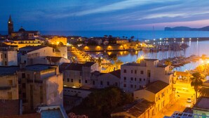A coastal town at dusk with illuminated buildings, a marina, and boats. - Bilo Agostino 2 in Alghero (Alghero)