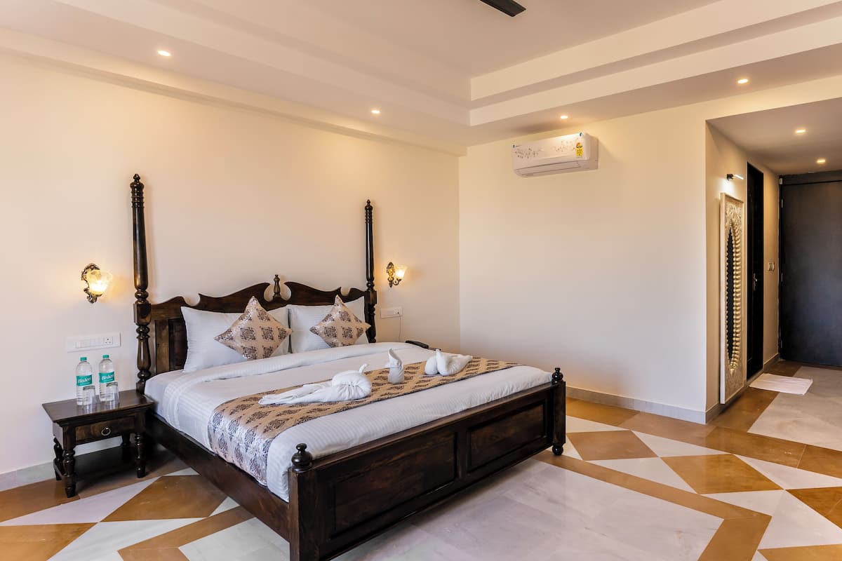 Un dormitorio con una cama grande, dos mesitas de noche y un aire acondicionado de pared.