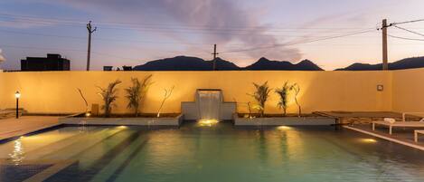 Una piscina con vista a las montañas al atardecer.