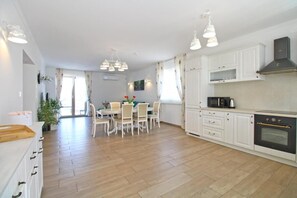 Una cucina moderna con mobili bianchi, un forno nero e un'area pranzo con tavolo e sedie.