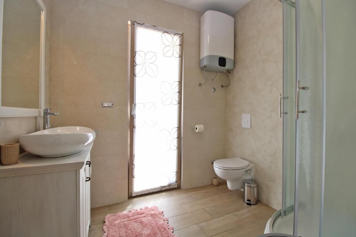 Un baño con un lavamanos grande y blanco, un inodoro y una cabina de ducha con mampara de vidrio.