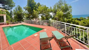 A swimming pool with a tiled deck, two lounge chairs, and a white railing. - P67- Playetas- ServHouse (Oropesa)